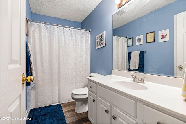 full bath featuring visible vents, toilet, vanity, wood finished floors, and a textured ceiling