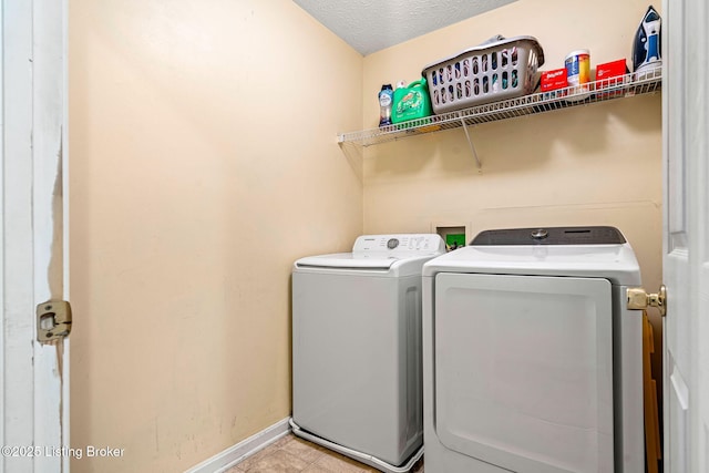 washroom with light tile patterned floors, baseboards, laundry area, a textured ceiling, and washer and dryer