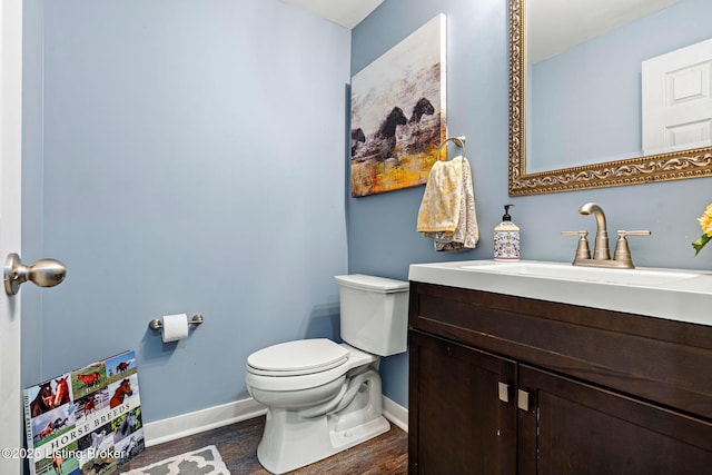 half bath with baseboards, toilet, wood finished floors, and vanity