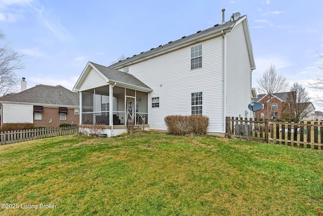 rear view of house with fence, a yard, and a sunroom