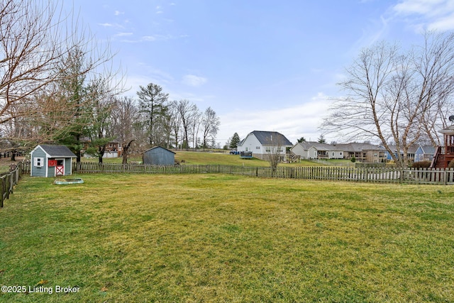 view of yard featuring an outdoor structure, a fenced backyard, a residential view, and a shed