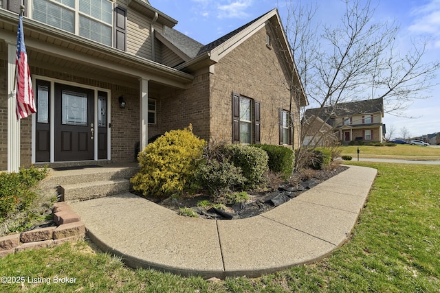 property entrance with a lawn and brick siding