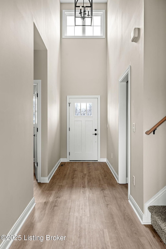 foyer entrance featuring stairway, a towering ceiling, and wood finished floors