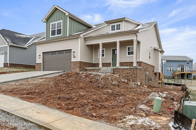 craftsman-style home with driveway, a porch, an attached garage, board and batten siding, and brick siding