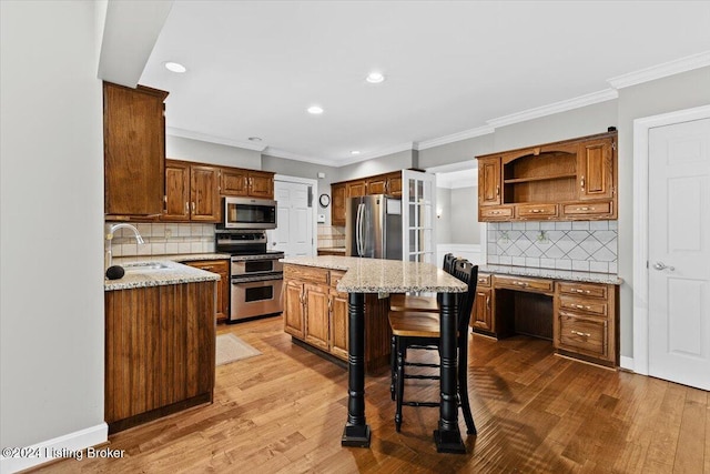 kitchen with wood finished floors, appliances with stainless steel finishes, a center island, and a sink