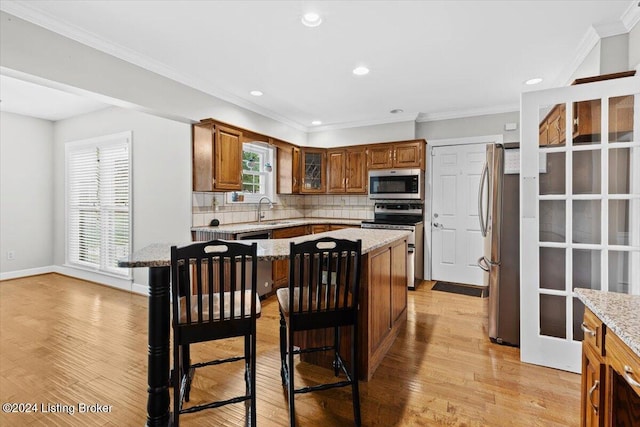 kitchen featuring a kitchen island, backsplash, stainless steel appliances, and light wood-style flooring