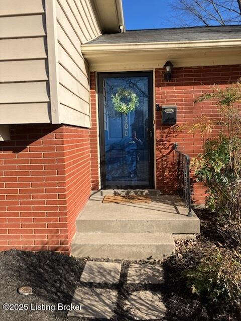 view of exterior entry featuring brick siding