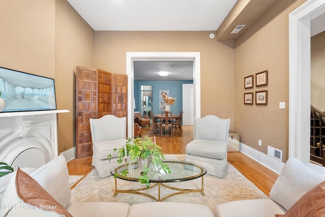 living room featuring visible vents, baseboards, and wood finished floors