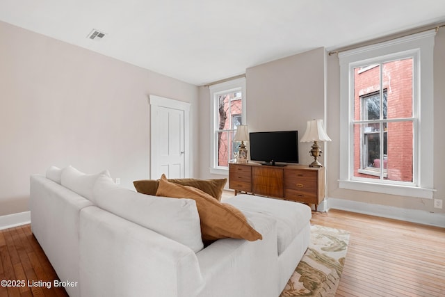 living area with light wood-style floors, visible vents, and baseboards