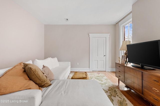 living area featuring visible vents, baseboards, and wood finished floors