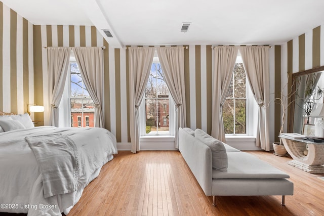 bedroom with wallpapered walls, visible vents, and light wood finished floors