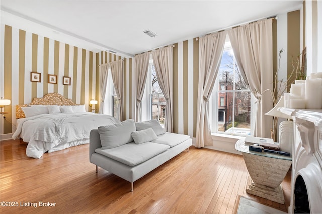 bedroom featuring wallpapered walls, multiple windows, light wood-style floors, and visible vents