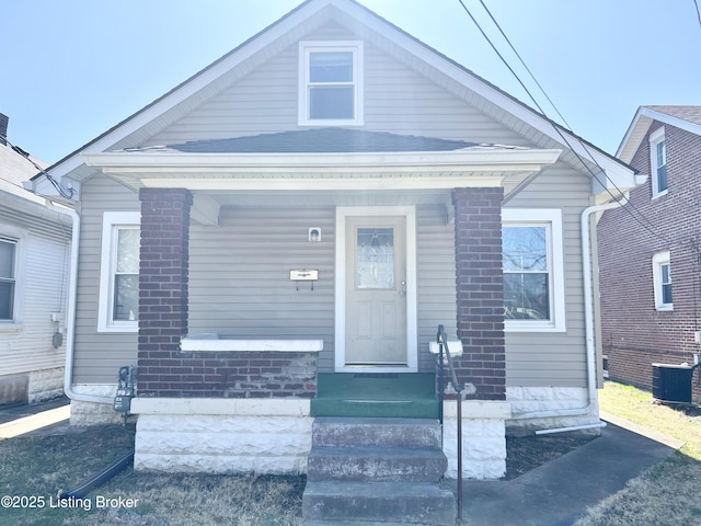 bungalow-style home with brick siding and central AC unit