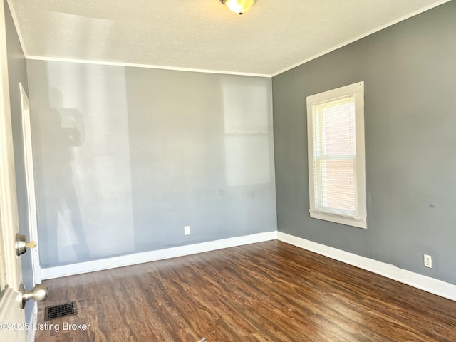 empty room featuring visible vents, baseboards, wood finished floors, and crown molding