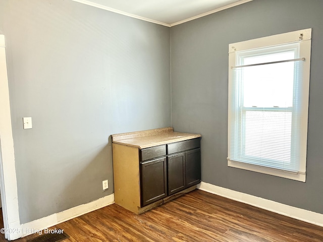 unfurnished room with dark wood-type flooring, baseboards, and ornamental molding