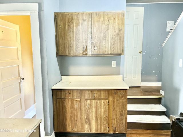 kitchen with baseboards, brown cabinetry, and light countertops