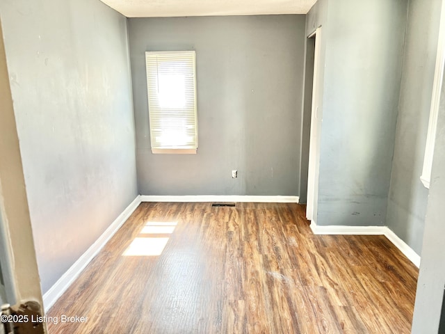 spare room with visible vents, baseboards, and wood finished floors