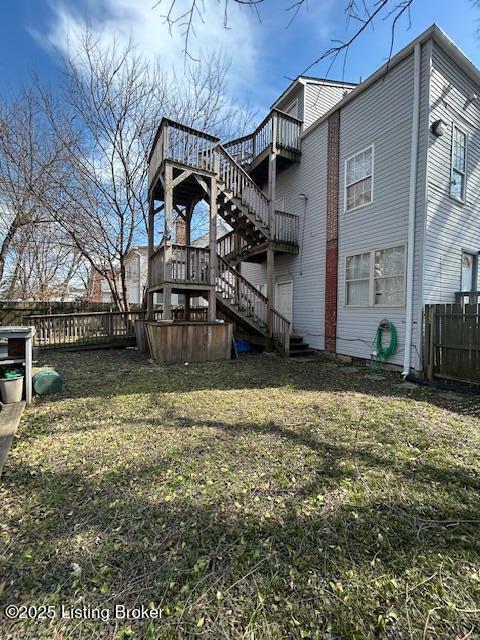 back of house with stairway, a yard, and fence