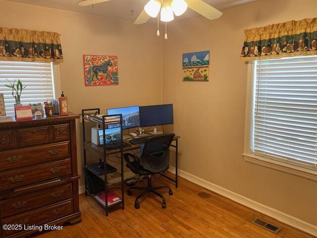 office space featuring baseboards, wood finished floors, visible vents, and ceiling fan