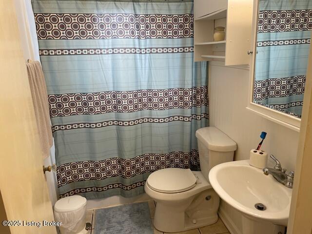 bathroom with a sink, curtained shower, toilet, and tile patterned floors
