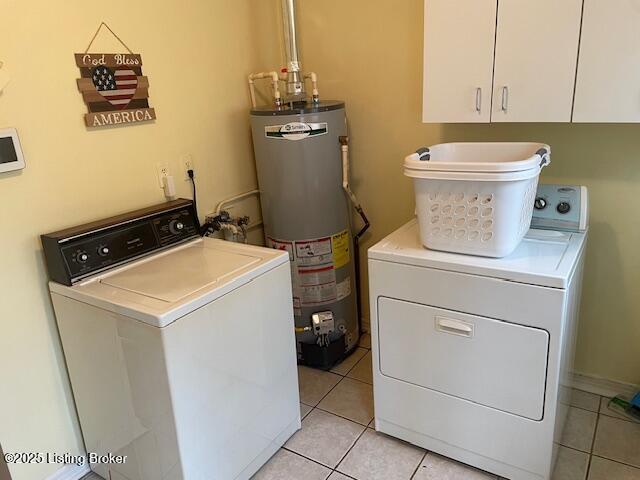 washroom featuring light tile patterned floors, cabinet space, water heater, and washing machine and clothes dryer