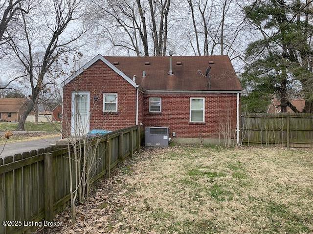 back of house with a yard, brick siding, central AC unit, and fence