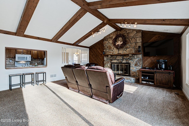 living area featuring visible vents, lofted ceiling with beams, a fireplace, carpet flooring, and a chandelier