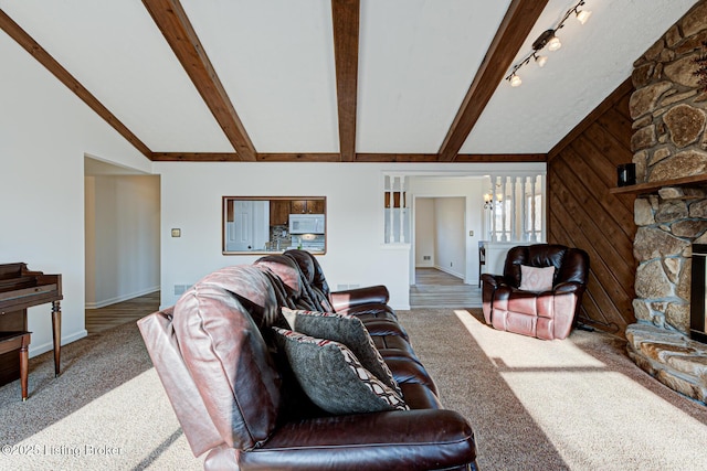 living area with vaulted ceiling with beams, wood walls, carpet flooring, a fireplace, and a notable chandelier