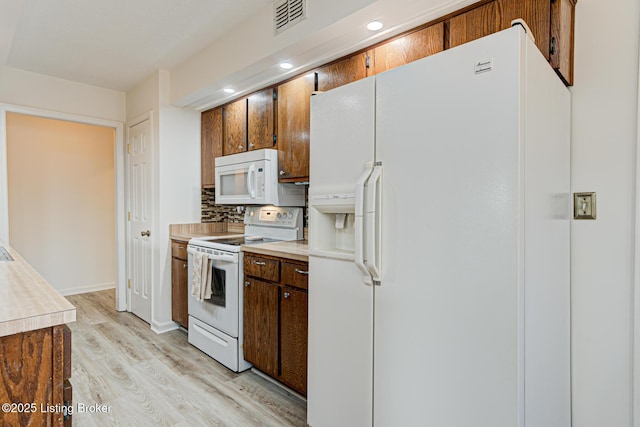 kitchen with visible vents, backsplash, white appliances, light wood-style floors, and light countertops