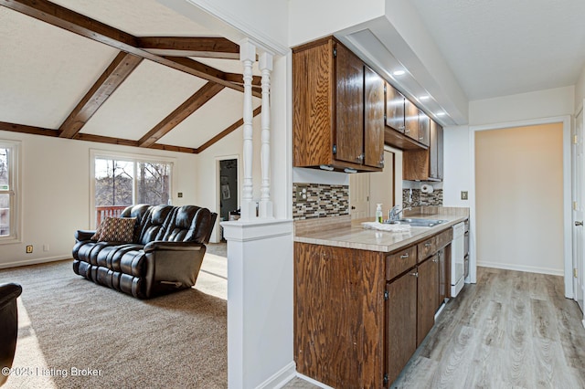 kitchen featuring lofted ceiling with beams, a sink, open floor plan, light countertops, and ornate columns