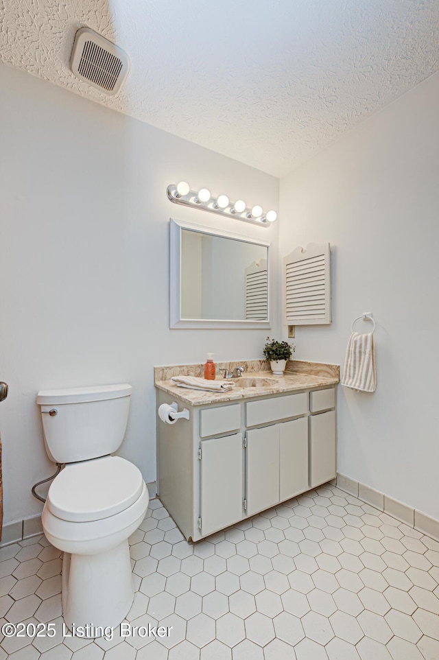 bathroom featuring tile patterned flooring, visible vents, toilet, vanity, and a textured ceiling