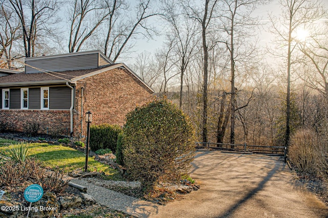 view of side of home featuring brick siding and roof with shingles