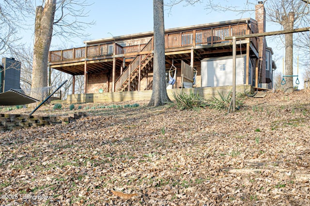 rear view of house featuring a wooden deck, a chimney, and stairs