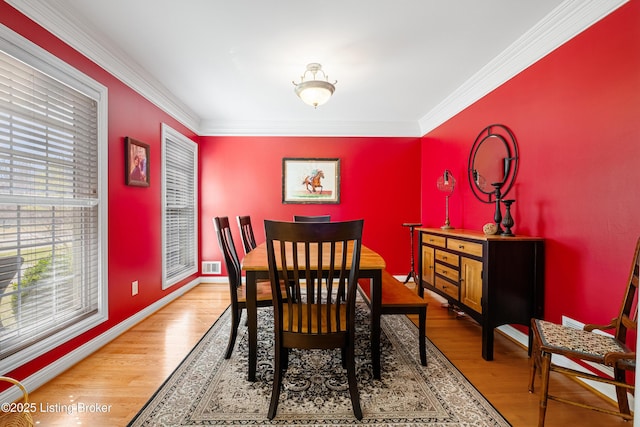 dining room with wood finished floors, visible vents, and ornamental molding