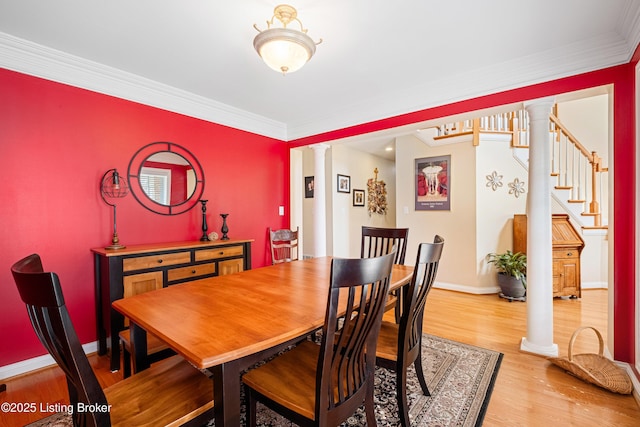 dining room featuring crown molding, baseboards, light wood-style floors, and ornate columns