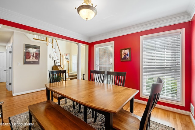 dining space with light wood finished floors, baseboards, stairs, and ornate columns