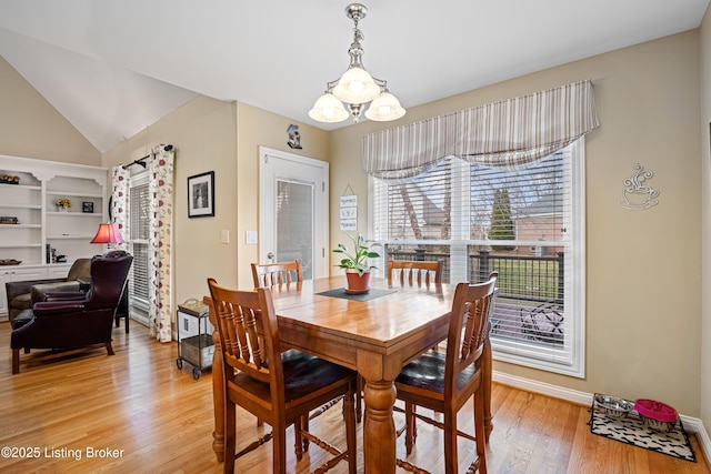 dining space featuring lofted ceiling, baseboards, light wood-type flooring, and a chandelier