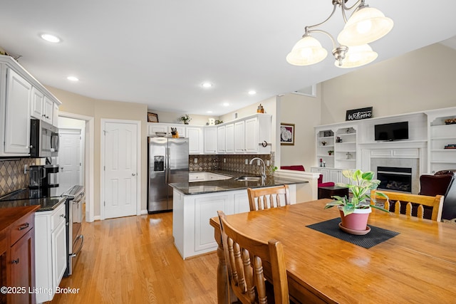 dining area featuring light wood finished floors, recessed lighting, and a fireplace