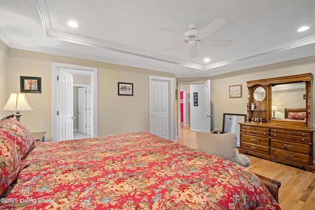 bedroom with light wood finished floors, ceiling fan, a tray ceiling, ornamental molding, and recessed lighting