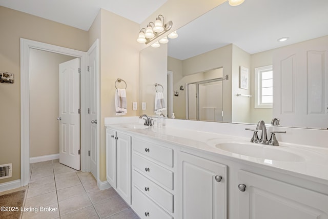 bathroom featuring a sink, double vanity, a shower stall, and tile patterned flooring