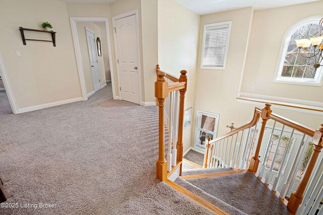 staircase with a notable chandelier, baseboards, and carpet