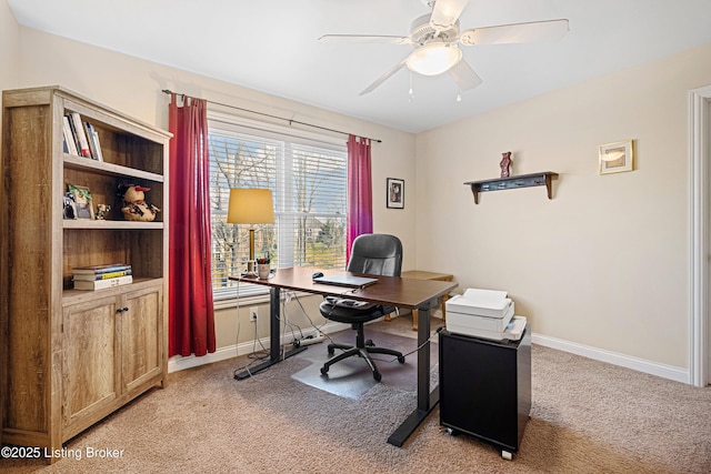 office featuring a ceiling fan, light colored carpet, and baseboards