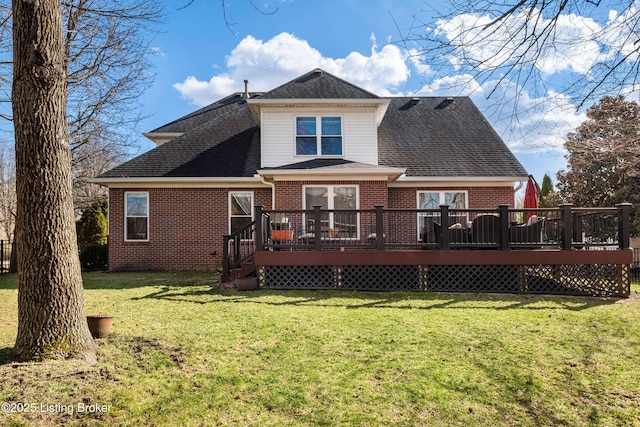 back of property with a yard, brick siding, roof with shingles, and a wooden deck