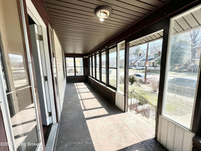 unfurnished sunroom featuring a healthy amount of sunlight and a residential view