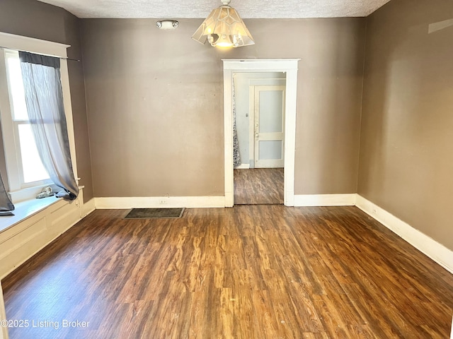 unfurnished room with baseboards, a textured ceiling, and wood finished floors