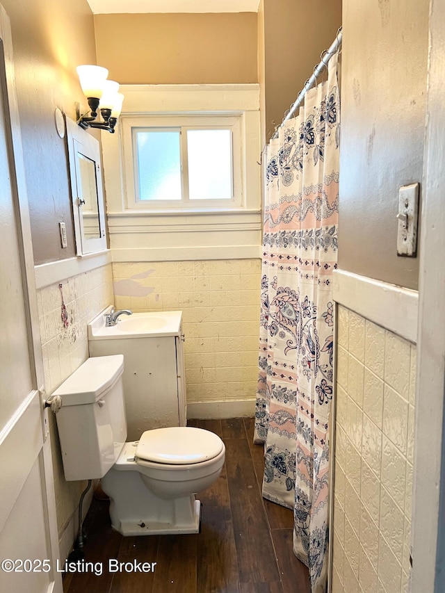 full bathroom with a wainscoted wall, toilet, tile walls, and wood-type flooring