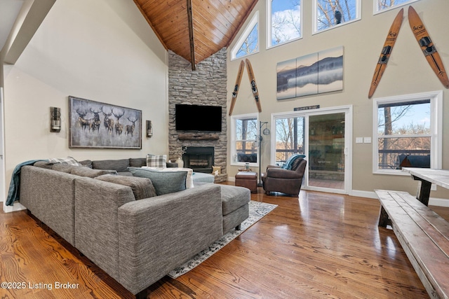 living area featuring wood finished floors, baseboards, a fireplace, vaulted ceiling, and wooden ceiling