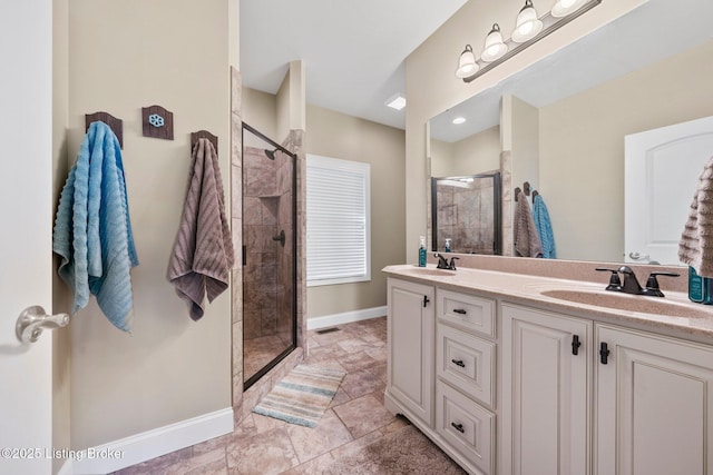 full bath with visible vents, baseboards, double vanity, tiled shower, and a sink