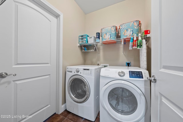 clothes washing area featuring dark tile patterned floors, washing machine and dryer, and laundry area