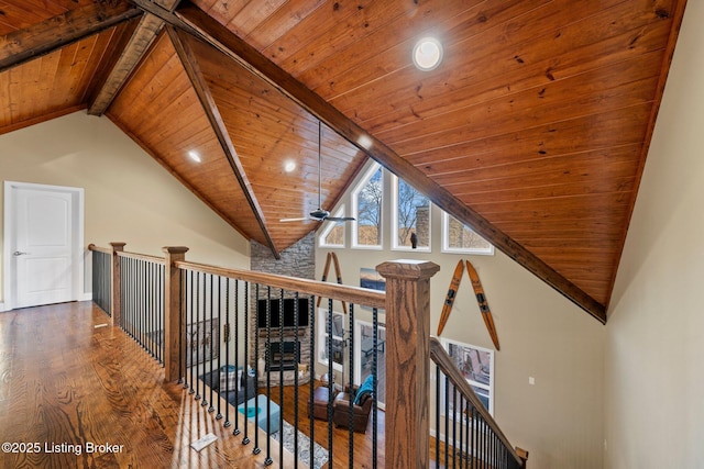 hall with beam ceiling, wood ceiling, an upstairs landing, and wood finished floors